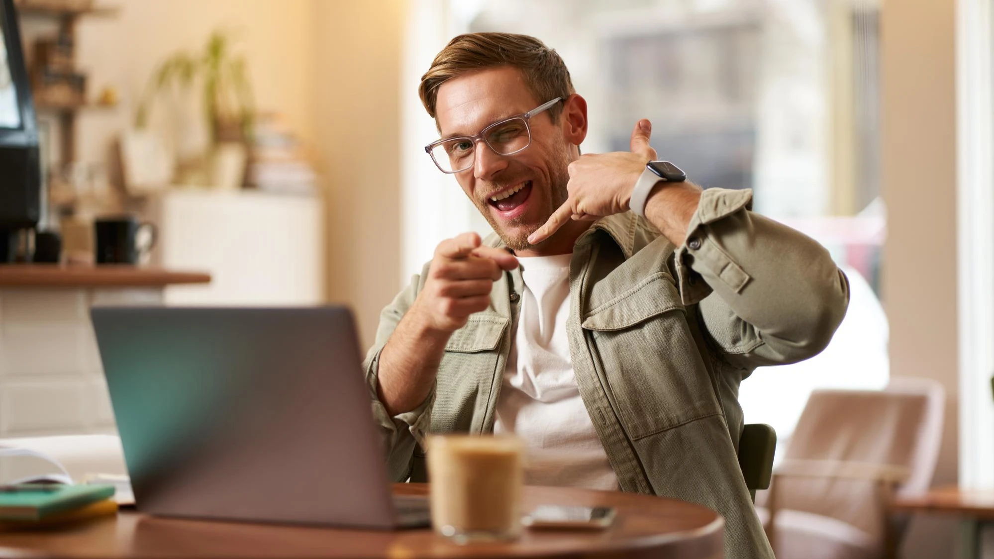 Persona trabajando en su laptop y haciendo un gesto amigable de contacto, simbolizando soporte y comunicación directa.