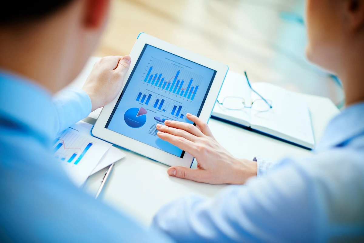Equipo revisando informes y gráficos en una tablet, ilustrando análisis de datos y seguimiento de resultados.